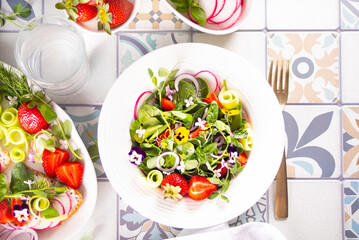 Spring healthy fresh salad with green, edible flowers pansies viola and strawberries