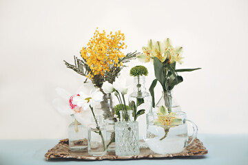 Different vases and glasses on metal tray with beautiful flowers on white background