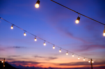 Festoon string lights decoration at the party event festival against sunset sky. light bulbs on...