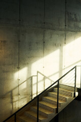 Part of poor lit interior of abandoned building with concrete slabs forming wall along of which there is staircase with metallic fencing