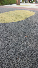Black asphalt. Pebble stone flooring with epoxy resin in city park. Pebble stone is yellow and red.