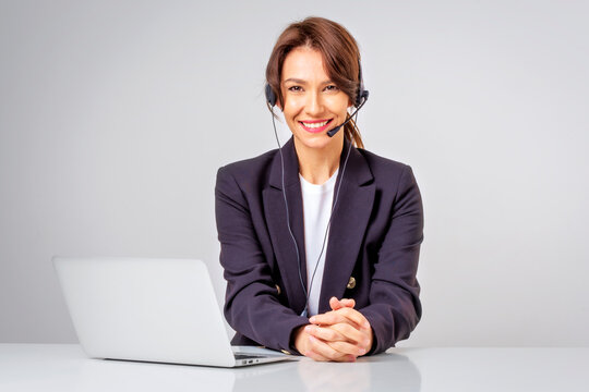 Studio portrait of a call center assistant business woman using headseat and laptop against isolated background