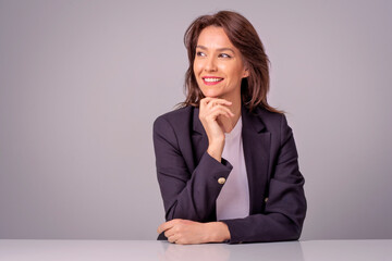 Attractive brunette haired woman sitting at isolated background