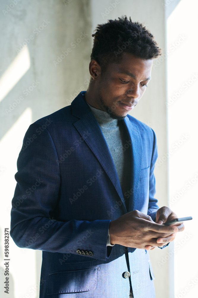 Aufkleber young serious african american businessman in formalwear using mobile phone while texting in front o