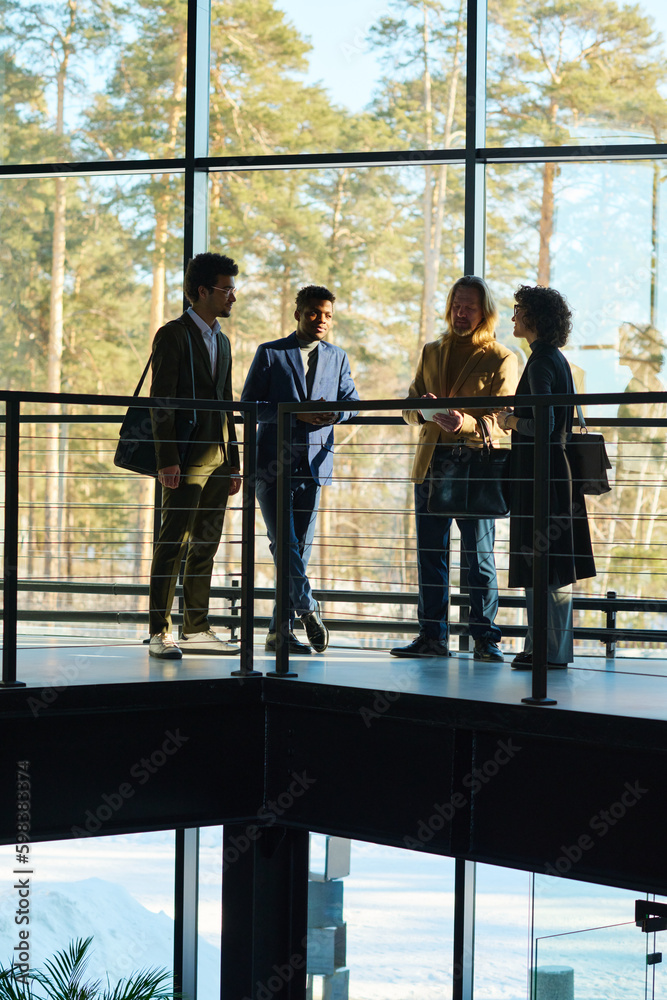 Aufkleber working meeting of four intercultural employees in formalwear standing against large window in corri