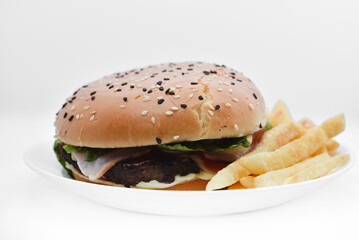 Meat burger with French fries on a white plate. Delicious fast food breakfast. Hamburger.