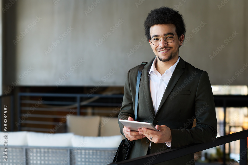 Aufkleber Happy young multi-ethnic businessman in formalwear looking at camera with smile while working with online data for project in tablet