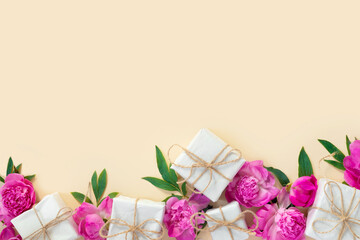 Bouquet of beautiful pink peonies with gift boxes in wrapping paper on yellow background. Festive greeting card.  Creative background with copy space for text.