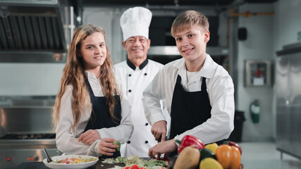 Portrait of Chef and students cooking and preparing food in kitchen. Cooking class for children....