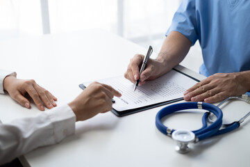 Close up view of doctor in doing paperwork at workplace, filling paper medical records.