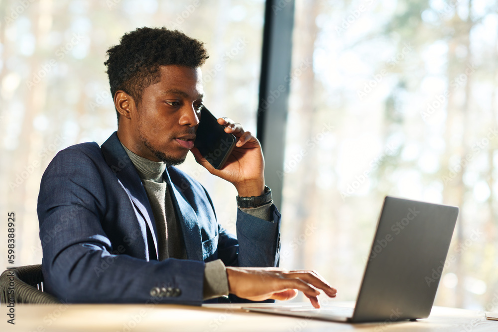 Aufkleber young confident male broker or agent talking to client on smartphone while sitting by workplace in f