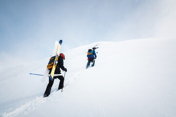Side view of a group of people climbers skiers climbing up the snowy slope. Snow-capped mountains and trekking, free skiing
