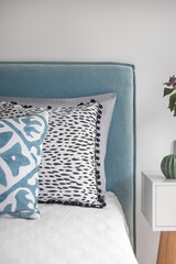 bedroom interior, details, blue headboard, colorful pillows and bedside table