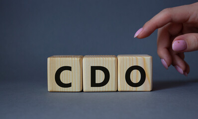 CDO - Collateralized Debt Obligation symbol. Wooden cubes with word CDO. Beautiful grey background. Businessman hand. Business and Collateralized Debt Obligation concept. Copy space.