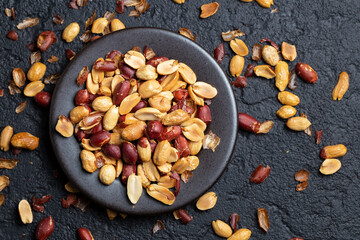 Pile of roasted peanuts on black background, space for text