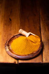 Turmeric Powder in a Wooden Spoon and Bowl