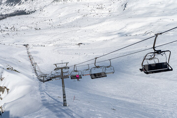 Cableway mountains with the gondolas. Stretched ropes on the racks of the cable railway against the background of snow