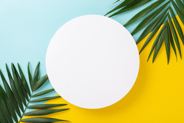 Summer relaxation getaway concept. Top view flat lay of palm leaves on blue and yellow background...