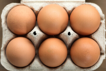 Close up view eggs in carton box. Fresh chicken natural farm egg in package on table cardboard. Brown eggs in recyclable carton package top view.