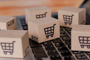 Shopping online. Cardboard box with a shopping cart logo on laptop keyboard. Shopping service on The online web. offers home delivery.