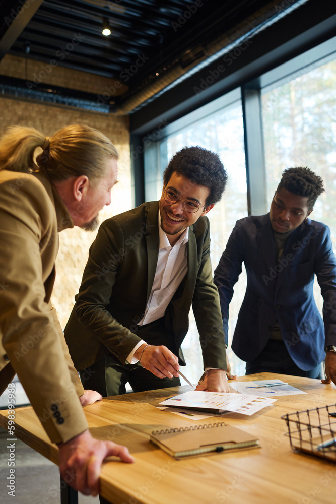 Aufkleber happy young male broker looking at mature colleague or boss while pointing at financial document on 