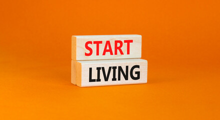 Start living symbol. Concept words Start living on beautiful wooden block. Beautiful orange table...