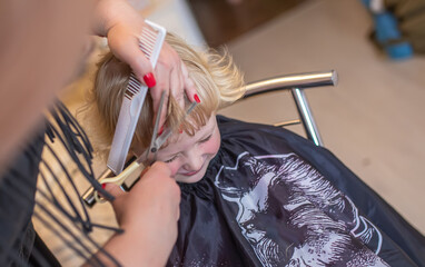 child sits patiently as a professional hairdresser trims her hair.