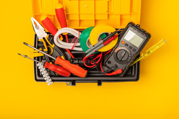 Electrician equipment on yellow background with copy space.Top view.Electrician tool set.Multimeter, tester,screwdrivers,cutters,duct tape,lamps,tape measure and wires.Flet lay. © Avocado_studio