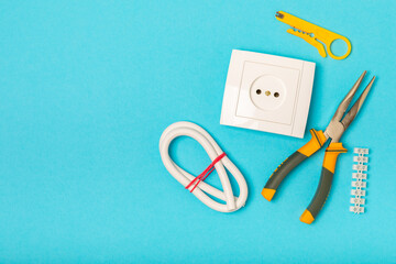 Electrician equipment on blue background with copy space.Top view.Electrician tool set.Multimeter, tester,screwdrivers,cutters,duct tape,lamps,tape measure and wires.Flet lay. © Avocado_studio