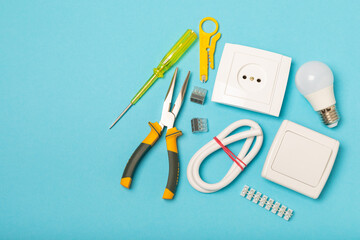 Electrician equipment on blue background with copy space.Top view.Electrician tool set.Multimeter, tester,screwdrivers,cutters,duct tape,lamps,tape measure and wires.Flet lay. © Avocado_studio