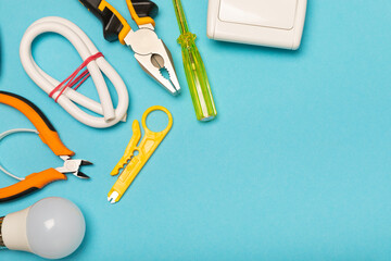 Electrician equipment on blue background with copy space.Top view.Electrician tool set.Multimeter, tester,screwdrivers,cutters,duct tape,lamps,tape measure and wires.Flet lay. © Avocado_studio