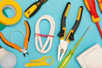 Electrician equipment on blue background with copy space.Top view.Electrician tool set.Multimeter, tester,screwdrivers,cutters,duct tape,lamps,tape measure and wires.Flet lay. © Avocado_studio