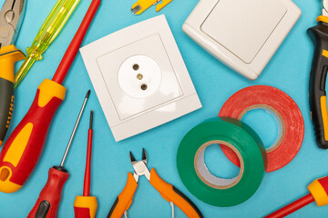 Electrician equipment on blue background with copy space.Top view.Electrician tool set.Multimeter, tester,screwdrivers,cutters,duct tape,lamps,tape measure and wires.Flet lay. © Avocado_studio