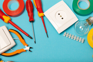 Electrician equipment on blue background with copy space.Top view.Electrician tool set.Multimeter, tester,screwdrivers,cutters,duct tape,lamps,tape measure and wires.Flet lay. © Avocado_studio