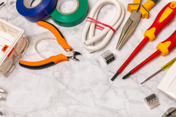 Electrician equipment on white background with copy space.Top view.Electrician tool set.Multimeter, tester,screwdrivers,wire pliers,duct tape, lamps, tape measure and wires.Flet lay. © Avocado_studio
