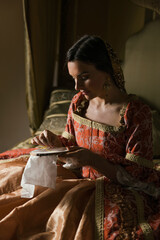 Renaissance woman sewing on her bed © Anneke