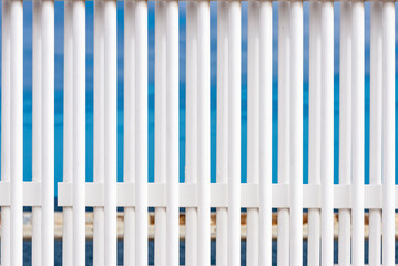 Bars of a white fence against the blue sky