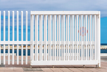 Bars of a white fence against the blue sky