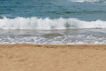 Beach sand and sea. Sea water with foam washes ashore on the sand