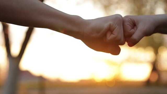 Family teamwork. Father and child bumping fists together outdoors on sunset. Punching friendly greeting. Good friendly relation, trust, understanding, respect concept. Best friends