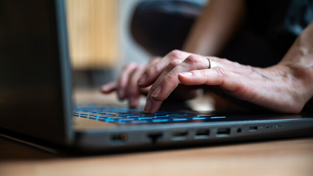 Low angle closeup view of female hands using laptop computer
