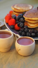 Pancakes with berries, tea. Warm light.