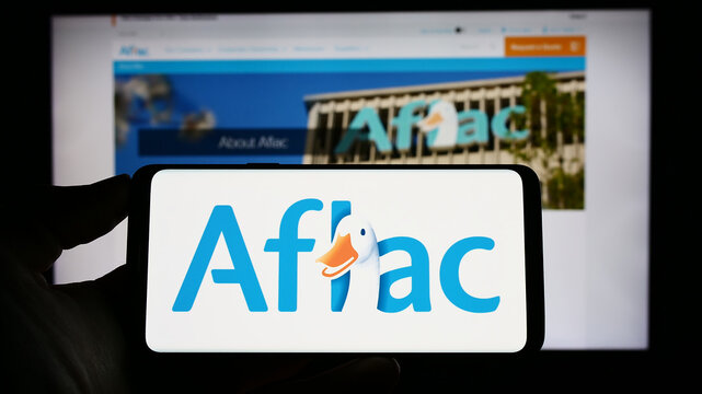 Stuttgart, Germany - 04-26-2023: Person holding smartphone with logo of US insurance company Aflac Inc. on screen in front of website. Focus on phone display.