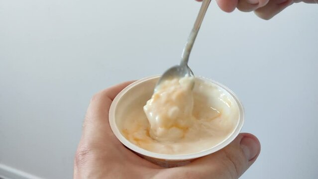 Man stirs pudding with rice in a jar with a spoon. Pudding or yogurt in the jar