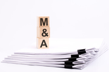 wooden blocks with text M and A on white table, stack white paper on background