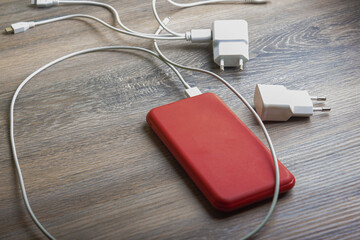 Chargers for phones in red and white colors on a wooden table