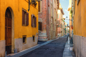 Fototapeta na wymiar Cozy narrow medieval street with colorful buildings in Verona town, Veneto, Italy, Empty Italian street in old town