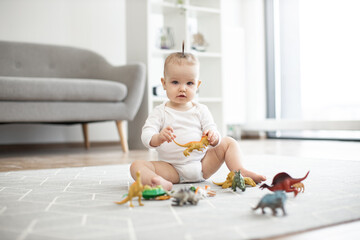 Portrait of cute little child in casual baby clothes posing with colorful animals while resting on...