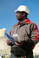 African american worker stands at construction site with work papers