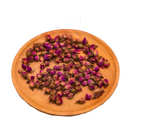 Dried rose buds on a wooden plate